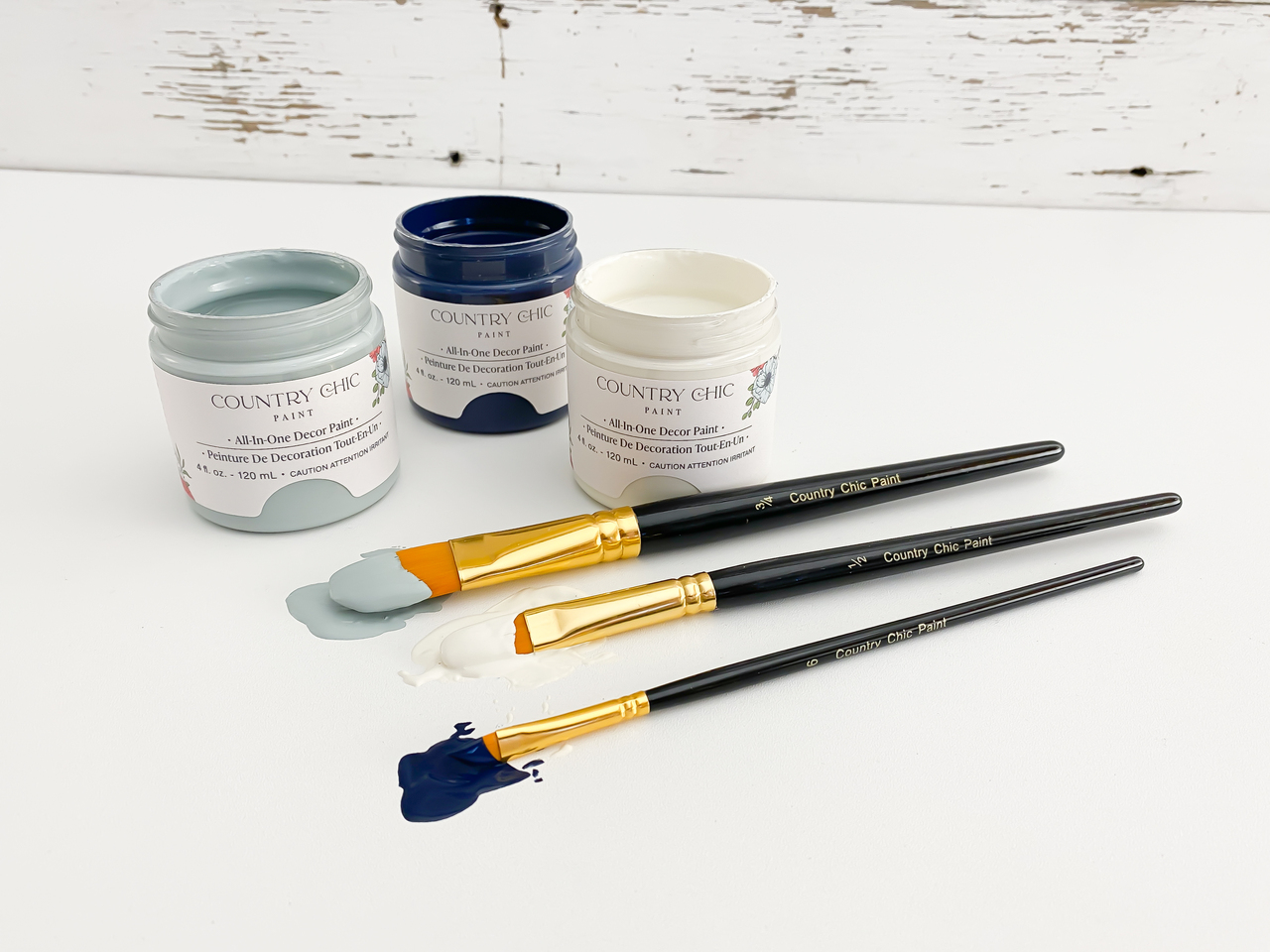 artist brushes dipped in paint with three paint jars