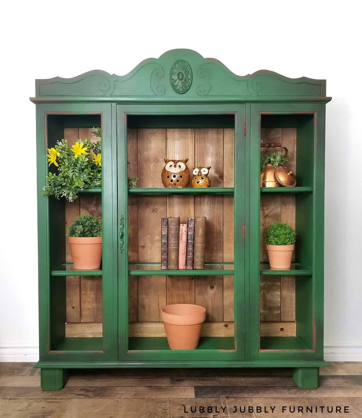 Rustic green storage cabinet with wood panelling and emerald green painted doors