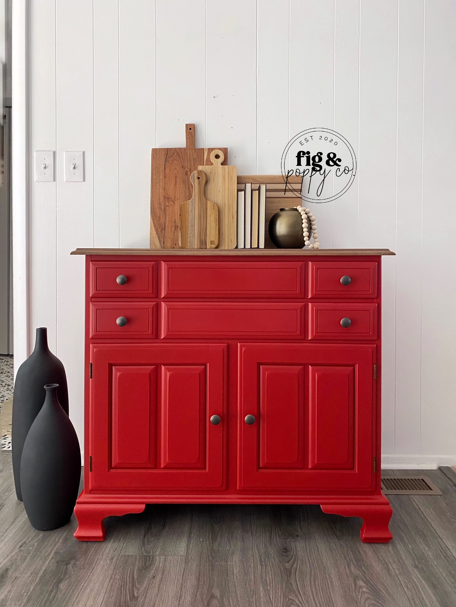 petite farmhouse cabinet in bold radiant red, two drawers and two doors, wodden cutting board, books, floor vases