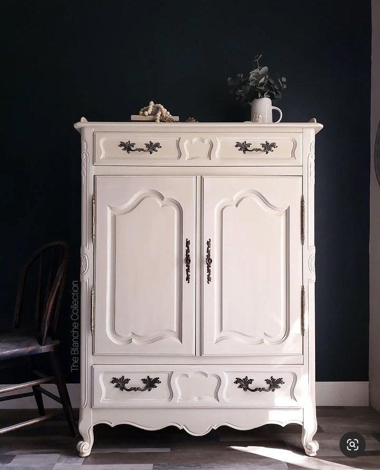 Off white painted wardrobe with ornate black handles against a black painted wall